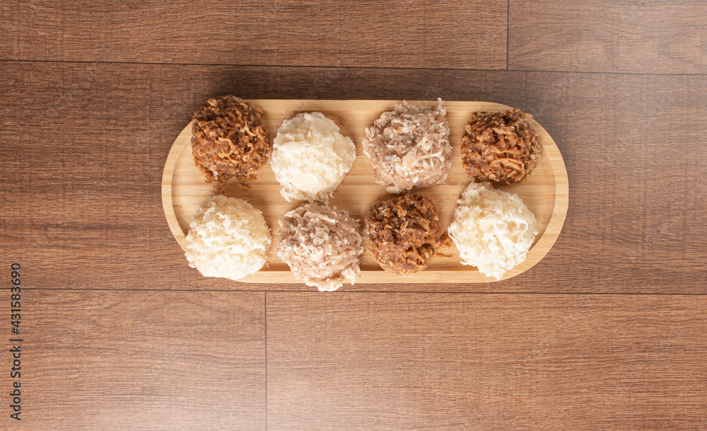 Cocada, Coconut candy from Brazil, white and brown cocadas on wooden surface, black background, top view. Cocada, Coconut candy from Brazil, white and brown cocadas on wooden surface, black background, top view.