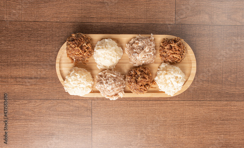 Cocada, Coconut candy from Brazil, white and brown cocadas on wooden surface, black background, top view.