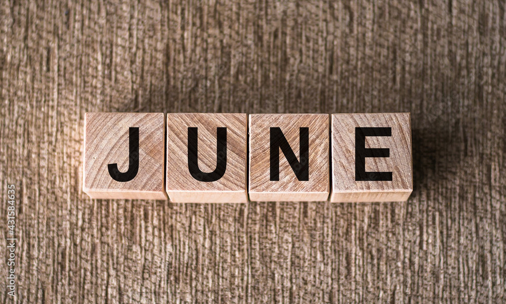 Fototapeta premium JUNE word written on wooden blocks on a brown background.