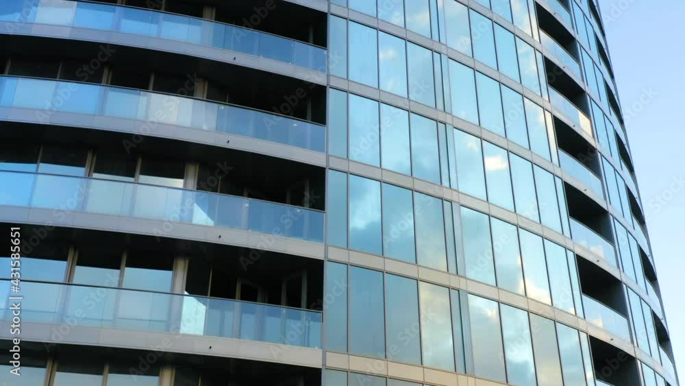Aerial side view of glass skyscraper with sky reflection in windows at sunset Aerial side view of glass skyscraper with sky reflection in windows at sunset