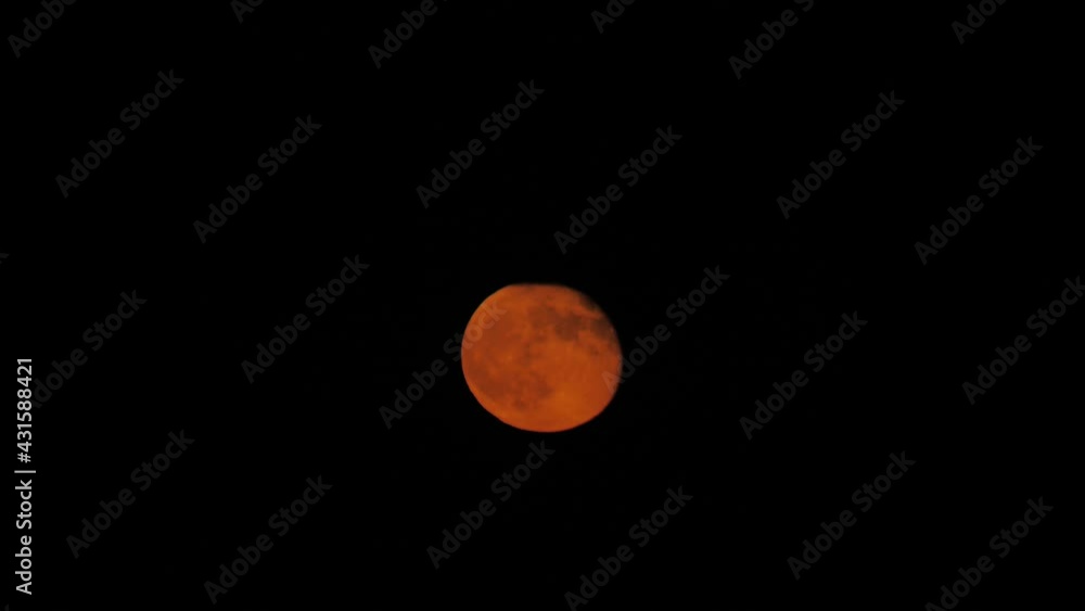 Beautiful red moon moves quickly behind the black clouds Beautiful red moon moves quickly behind the black clouds