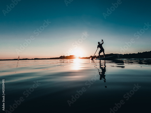 Mężczyzna na desce SUP o zachodzie słońca nad jeziorem