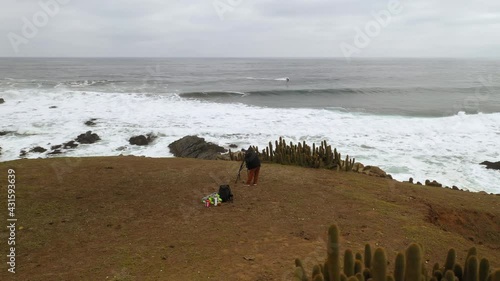 surf and nature photographer on the coast of chile, pacific ocean, pichilemu punta de lobos, drone footage, orbital plane, a jet ski in the background, swell