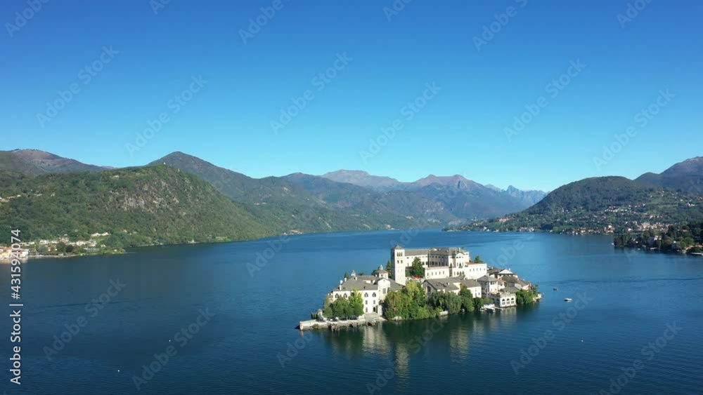 L'île Saint-Jules (Isola di San Giulio) au milieu du lac d'Orta entourée des montagnes et forêts verdoyantes dans le Piémont, vers les Alpes, en Italie, en drone, à l'automne L'île Saint-Jules (Isola di San Giulio) au milieu du lac d'Orta entourée des montagnes et forêts verdoyantes dans le Piémont, vers les Alpes, en Italie, en drone, à l'automne