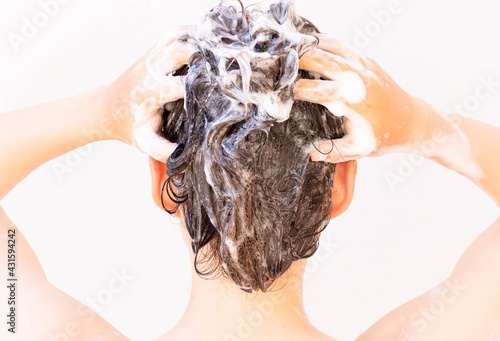 A person taking a shower washing hair and body. Shampoo and water.