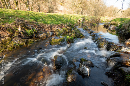 Long exposure of the Weir Water river flowing through the valley at Robbers Bridge in Exmoor National Park