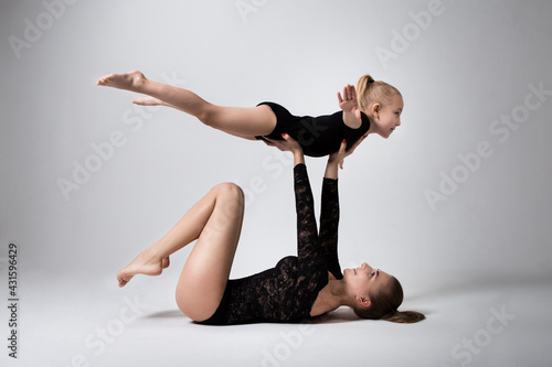 Mother lying down holding her daughter, she raised her hands imagining herself an airplane who loves to fly in the air