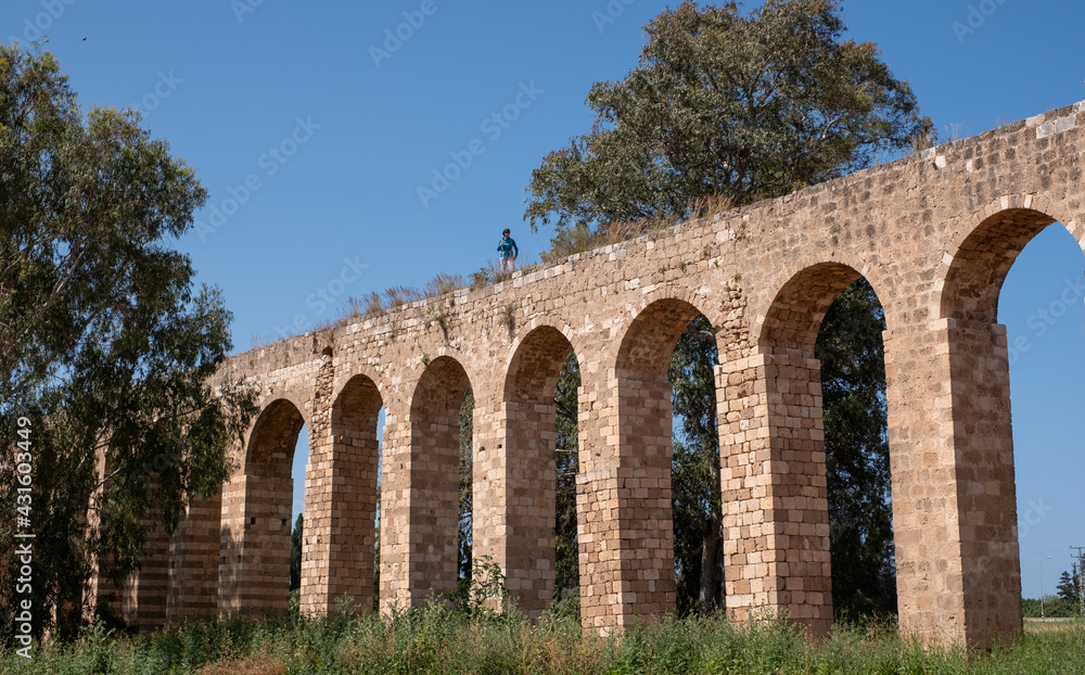 The 200 year old Ottoman aqueduct, supplied water from Cabri springs to Acco, western Galilee, Israel. Middle aged female posing at the upper line of the aqueduct.