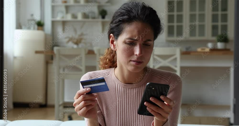 Woman holding credit card and smart phone experiences problems with e-payment. Female feels angry due lack of money, payment insecurity, insufficient, not enough funds. Victim of fraud, scam concept Woman holding credit card and smart phone experiences problems with e-payment. Female feels angry due lack of money, payment insecurity, insufficient, not enough funds. Victim of fraud, scam concept