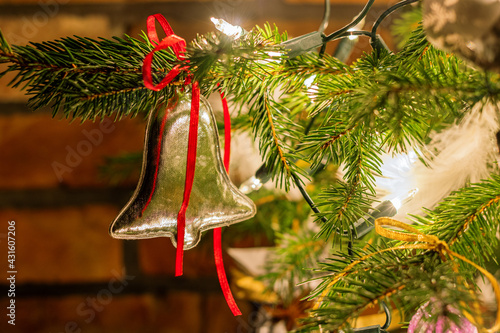 Silver bell with a red bow hung on a Christmas tree. Various Christmas decorations. Christmas background with a place for your wishes