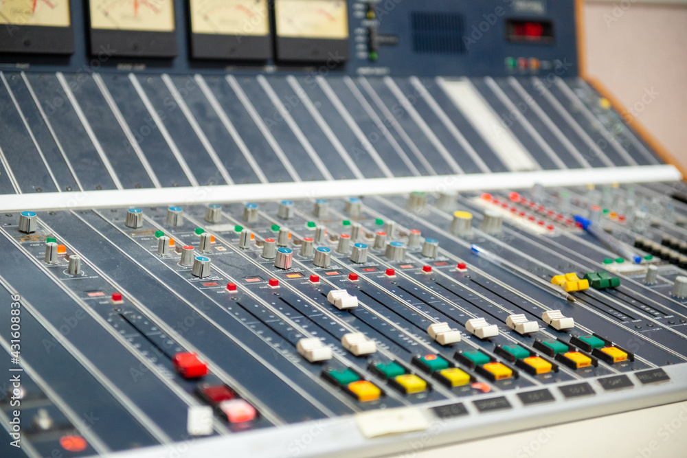  A closeup of a professional engineer entertainment recording blackboard. The board has a number of colorful buttons and sliders. The digital studio equalizer console is for producing music. 
