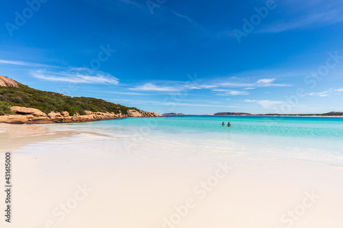 Fototapeta Naklejka Na Ścianę i Meble -  A young couple swim in the sparkling water next to the pristine white sand beach of Wharton Bay in the Cape LeGrande National Park on a clear summer day.