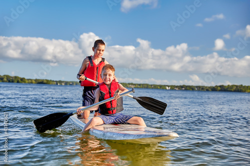 Boys having fun on a paddle board. Summer camp activity