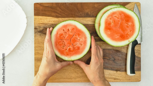 Watermelon slices on wooden cutting board, flat lay, woman hands