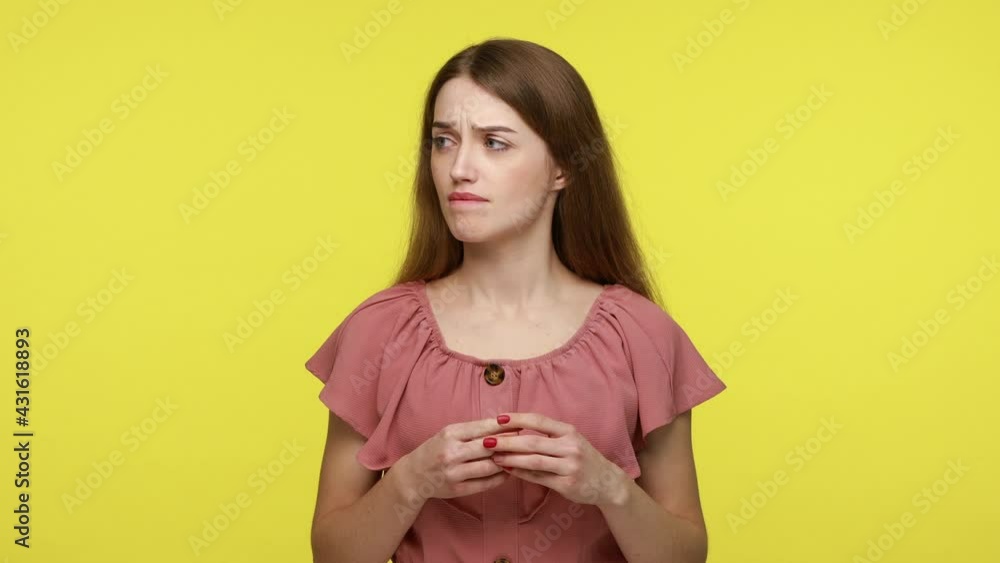 Scared brown haired girl in dress biting nails, feeling nervous before important occasion, in anticipation of bad event, feeling worried about troubles. Indoor shot isolated on yellow background. Scared brown haired girl in dress biting nails, feeling nervous before important occasion, in anticipation of bad event, feeling worried about troubles. Indoor shot isolated on yellow background.