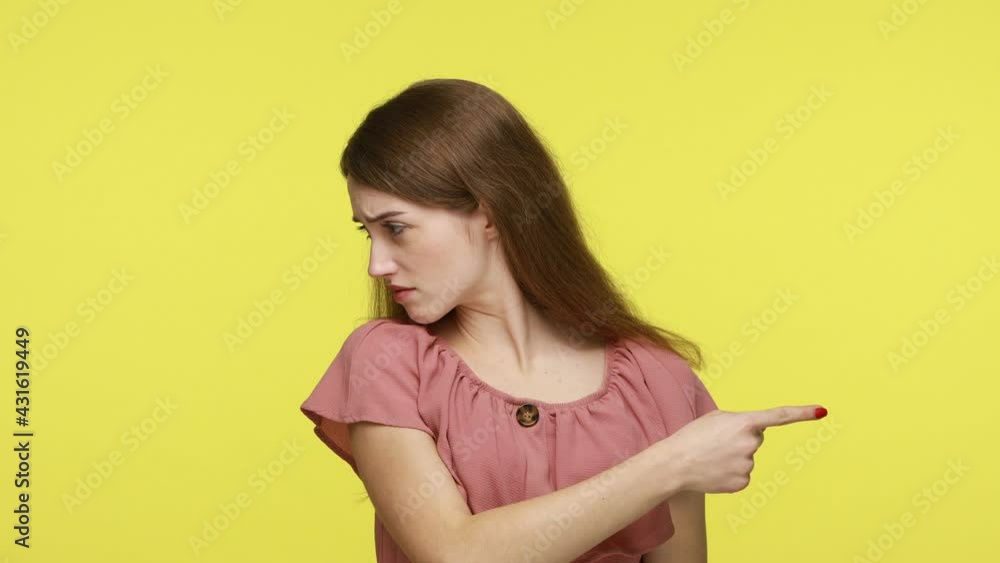 Annoyed unhappy woman in pink dress pointing finger away asking to get out, confused and disappointed with betrayal, ordering to leave someone immediately. Indoor shot isolated on yellow background. Annoyed unhappy woman in pink dress pointing finger away asking to get out, confused and disappointed with betrayal, ordering to leave someone immediately. Indoor shot isolated on yellow background.