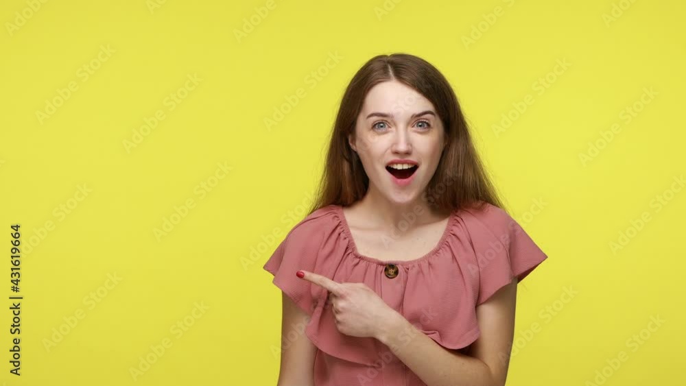 Overjoyed surprised girl pointing at copy space and looking excitedly, pointing at workspace mockup for advertisement, empty place for promotional image. Indoor shot isolated on yellow background. Overjoyed surprised girl pointing at copy space and looking excitedly, pointing at workspace mockup for advertisement, empty place for promotional image. Indoor shot isolated on yellow background.