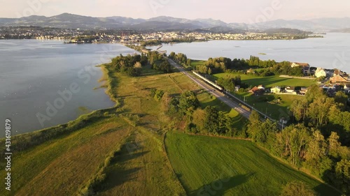 Aerial drone shot tilting up and showing SBB train driving towards Rapperswil Switzerland on a summer evening photo