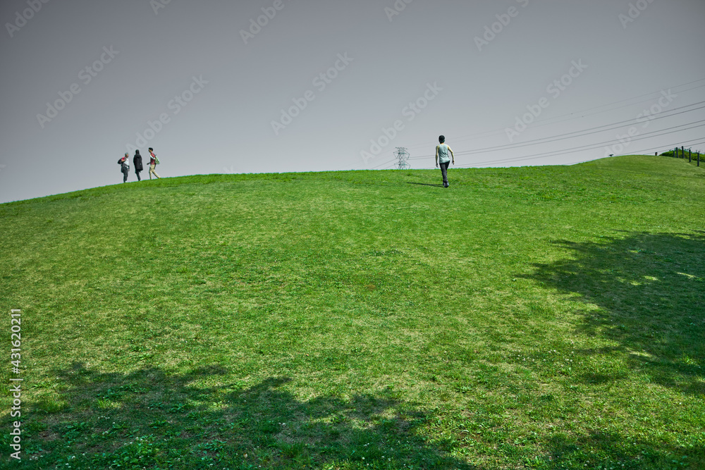公園の丘に登る家族と一人の男性