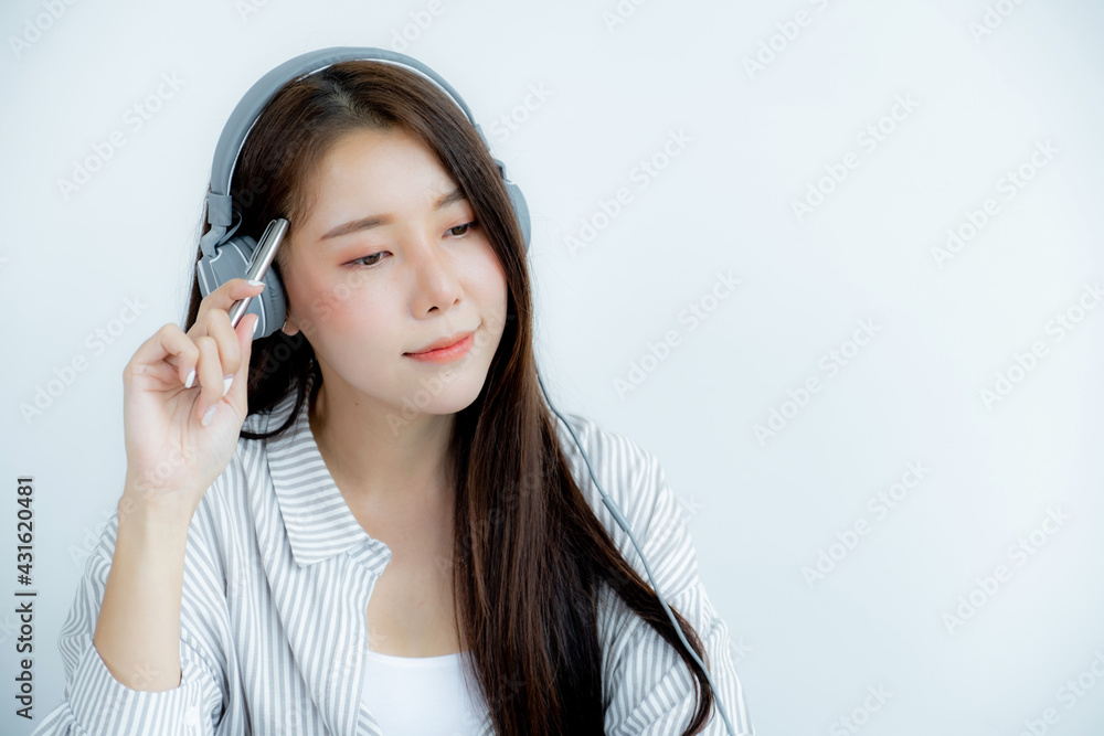 Close up of Asian woman portrait with headphones holding a pen looking straight ahead Close up of Asian woman portrait with headphones holding a pen looking straight ahead