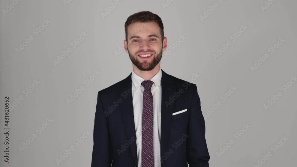 Young handsome businessman looking at camera, grey background, isolated, in suit and tie, looking tired Young handsome businessman looking at camera, grey background, isolated, in suit and tie, looking tired