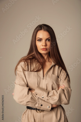 Portrait of young caucasian brunette woman in a beige blouse posing