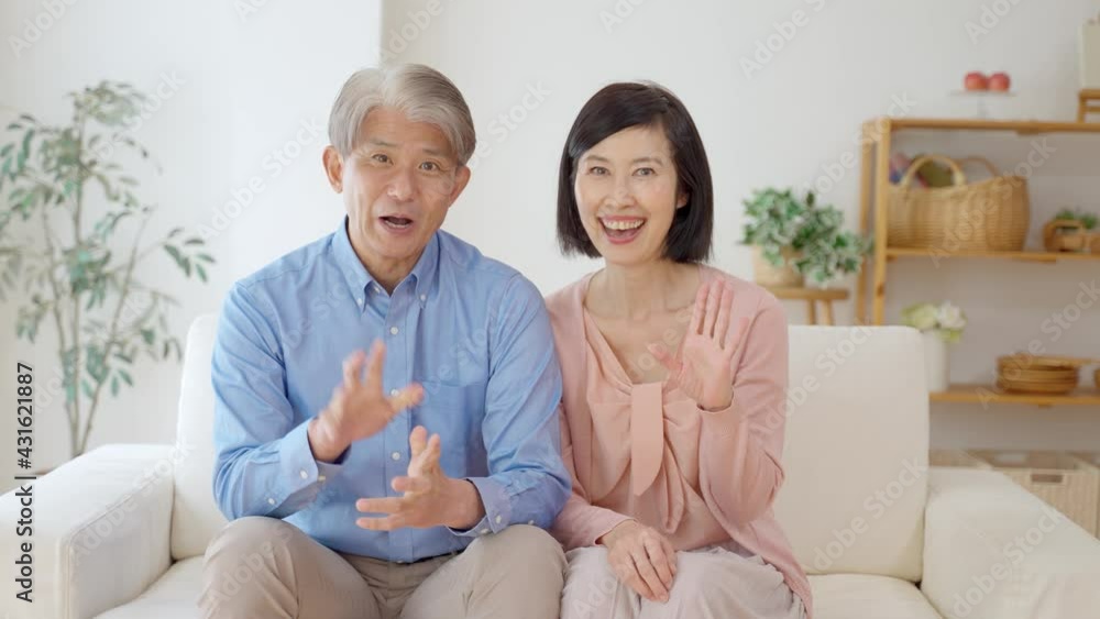 リビングでテレビ電話をするミドル夫婦 リビングでテレビ電話をするミドル夫婦
