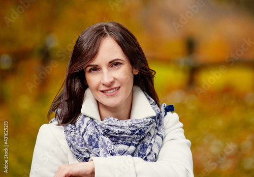 Cheerful smiling young blonde wrapped in blanket in autumn forest
