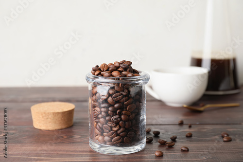 Jar with coffee beans on wooden background