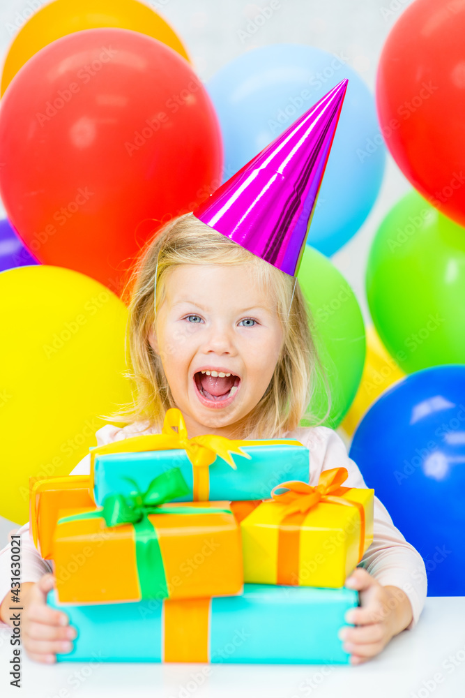 Obraz premium Happy little girl wearing party's cap holds many gift boxes