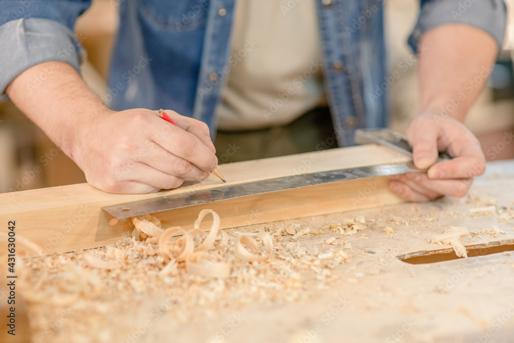 Carpenters hands taking measurement of a wooden plank Carpenters hands taking measurement of a wooden plank