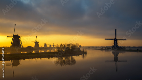 Traditionelle Windmühlen bei Sonnenaufgang im Nebel, Kinderdijk in Holland