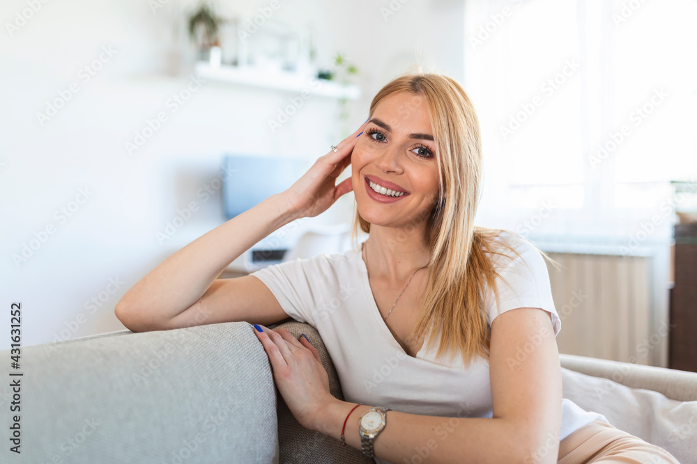 Smiling young woman relaxing while sitting on comfortable couch in living room. Weekend. Cheerful woman Sitting On Couch Relaxing At Home On Weekend Morning. Empty Space Smiling young woman relaxing while sitting on comfortable couch in living room. Weekend. Cheerful woman Sitting On Couch Relaxing At Home On Weekend Morning. Empty Space