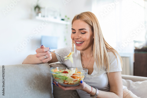 Healthy lifestyle woman eating salad smiling happy outdoors on beautiful day. Young female eating healthy food laughing and relaxing in sofa.