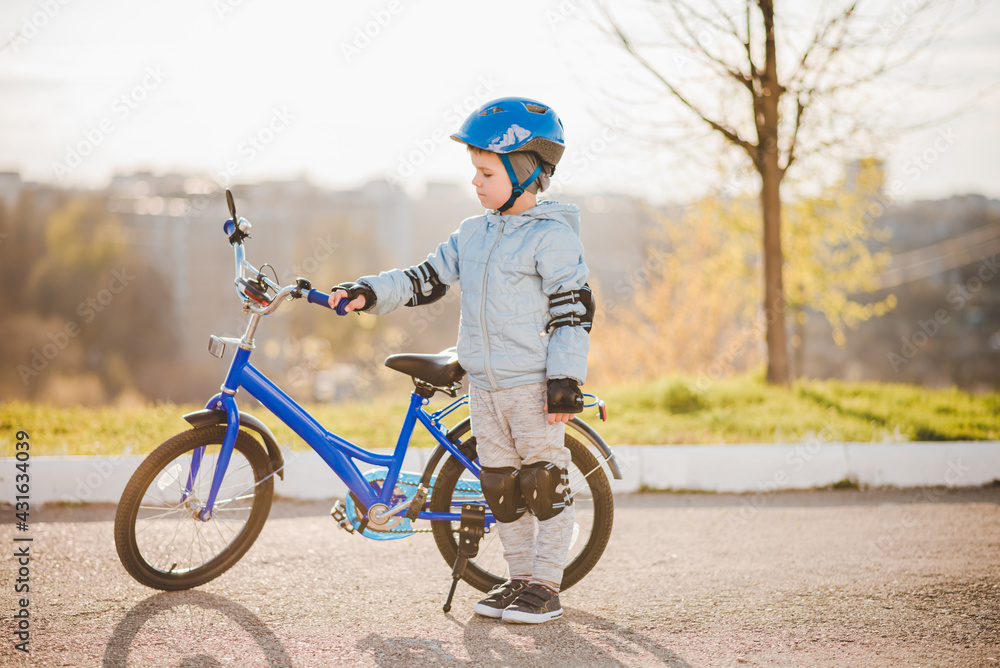 A child in a helmet learns to ride a bike on a sunny day at sunset A child in a helmet learns to ride a bike on a sunny day at sunset