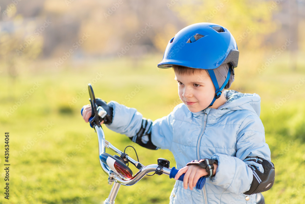 A child in a helmet learns to ride a bike on a sunny day at sunset A child in a helmet learns to ride a bike on a sunny day at sunset