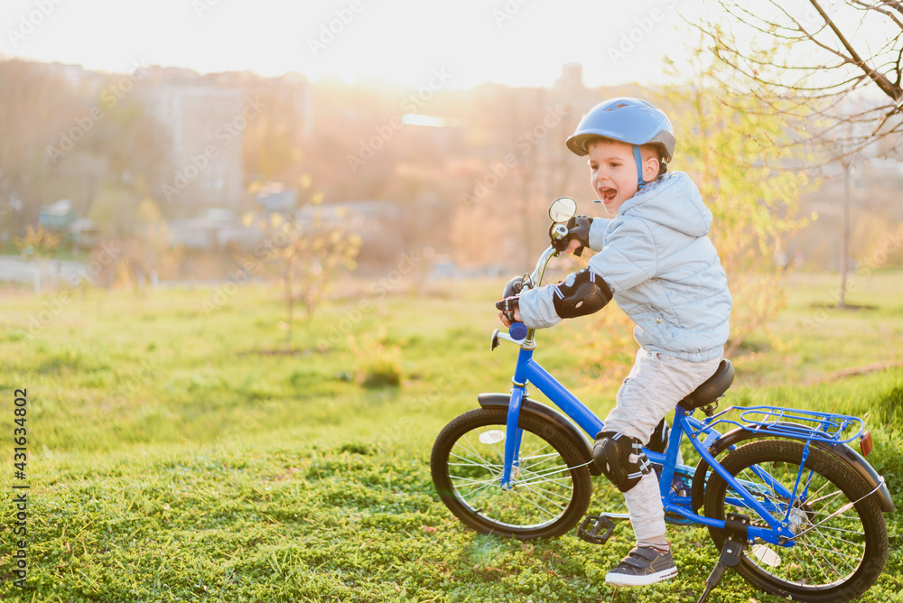 Fototapeta premium Little boy in helmet rides a bicycle on a sunny day