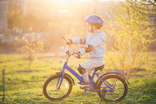 Fototapeta Naklejka Na Ścianę i Meble -  Little boy in helmet rides a bicycle on a sunny day