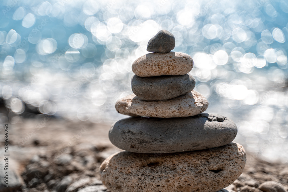 Tower of stones. Balanced pebble pyramid on the beach on a sunny day. Blue sea on the background. Selective focus, bokeh. Zen stones on the sea beach, meditation, spa, harmony, tranquility, balance Tower of stones. Balanced pebble pyramid on the beach on a sunny day. Blue sea on the background. Selective focus, bokeh. Zen stones on the sea beach, meditation, spa, harmony, tranquility, balance