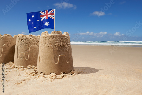 Australian flag on top of group of three sandcastles at the beach photo