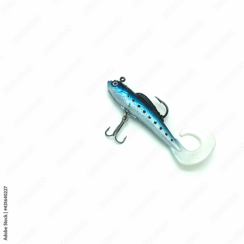 Fishing accessories. The bait is a blue silicone fish with two hooks. The flexible tail is curved. Isolated on a white background. Close-up Fishing accessories. The bait is a blue silicone fish with two hooks. The flexible tail is curved. Isolated on a white background. Close-up