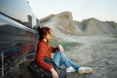 woman hiker in the mountains on nature sits near the car and mountains in the background sky road landscape