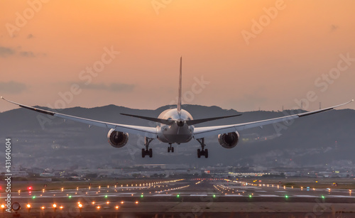 夕陽を背景に着陸する飛行機のイメージ photo