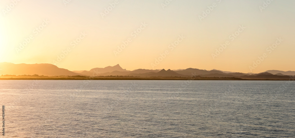 Looking over water towards Mount Warning and hills from Byron Bay at dusk Looking over water towards Mount Warning and hills from Byron Bay at dusk
