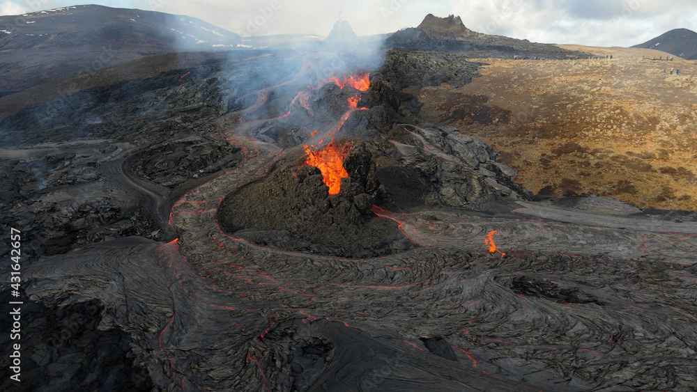 Fototapeta premium lava eruption volcano with snowy mountains, Aerial view Hot lava and magma coming out of the crater, April 2021 