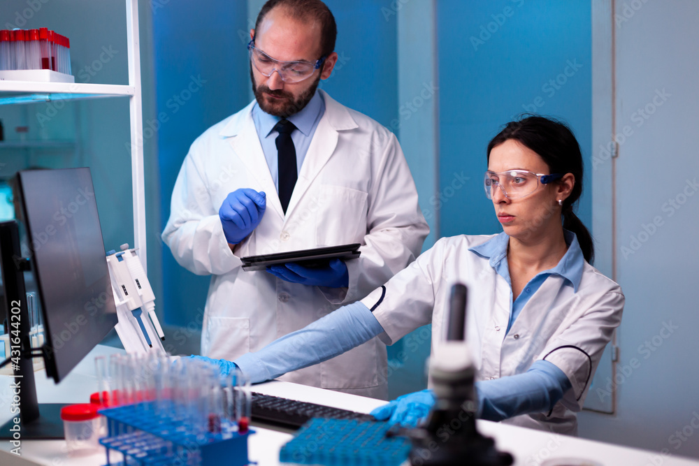 Woman scientist and man doctor studying virus expertise in medicine lab working with professional technology equipment. Doctors specialists discussing innovative treatment using high tech technology Woman scientist and man doctor studying virus expertise in medicine lab working with professional technology equipment. Doctors specialists discussing innovative treatment using high tech technology