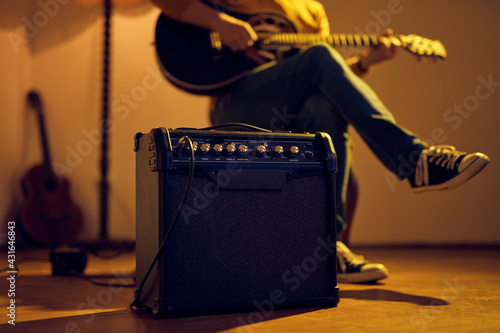 Fotografi Male musician playing acoustic guitar on the amplifier in retro vintage room