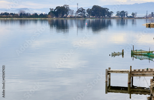 Wooden pier in a river with nets in the background and trees and mo.untains blurred on the horizon photo