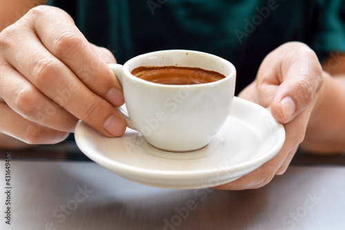Middle view  espresso in ceramic cup with woman hand.