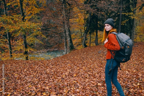 Traveler with a backpack in the autumn forest and hat sweater jeans fallen leaves lake trees